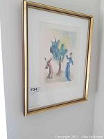 Full view of framed print hung on wall, showing gold-toned frame, mat and artwork.