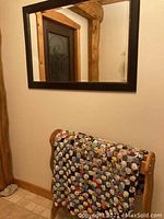 Wall mirror hanging above wooden quilt rack with Yo-Yo quilt draped on rack