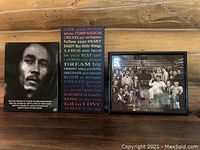 Three framed wall art pieces displayed on a wooden wall including Bob Marley print, colorful quote print, and movie villains collage.