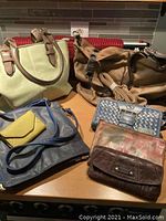 Lot of six purses displayed on a surface, showing different colors, styles, and material types.