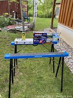 Wide image of the two Mastercraft saw horses with the various tools and items placed on top and around the stand in an outdoor setting.