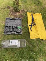 Full lot showing cordless drill in case, small live trap, and yellow rain pants