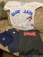 Photo showing the full set of Toronto Blue Jays jersey laid out with Toronto Maple Leafs sweatpants, t-shirt, and Nike Canada thermal fit hoodie.