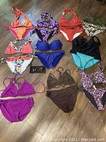 Overview of ten ladies bikinis in small and medium sizes with varied colors and patterns, plus one pair of sunglasses.