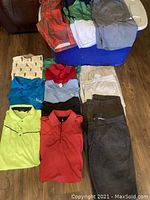 Image shows a collection of folded men's golf shirts, pants, shorts, and swimsuits in various colors and sizes.