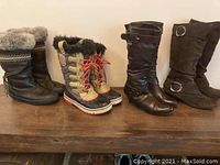Four pairs of size 6 ladies boots displayed on a wooden surface against a beige wall