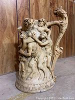 Full side view of large decorative pitcher with sculpted Greek/Roman inspired figures and dragon handle, showing full relief scene and base decoration, with Sharpie for scale