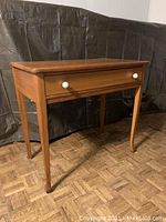 Front-side view showing single drawer and curved legs.