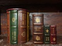Three book-style containers sitting on a shelf, showing titles and spines