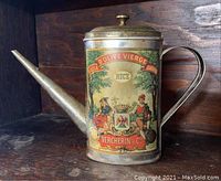 Side view of vintage metal olive oil can with long spout, lid, handle, and colorful label depicting two figures and a crest with text 'Huile d'Olive Vierge', 'Nice', 'Vercherin & Cie'