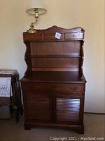 Full view of wooden dresser with backboard and lamp on top showing overall condition and style.
