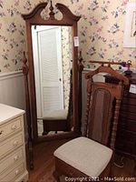 Full view of the standing mirror and valet chair in a room with floral wallpaper