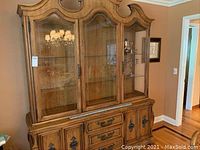 Front view of upper glass display section of china cabinet with carved wood and glass shelving