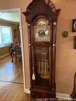 Full view of grandfather clock showing bonnet top, dial, pendulum and weights