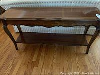 Front view showing entire wooden end table with visible polished wood grain and curved legs.