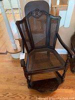 Front view showing chair construction, cane seat and backrest, armrests, and footrest.