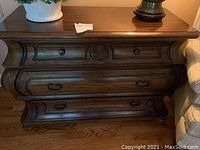 Front view of the heavy wood cabinet with drawers and decorative carvings