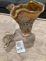Front and top view of the colored glass vase showing wavy rim and multicolor abstract pattern.