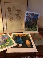 Overall view of all five artworks showing framed sketch and colorful prints