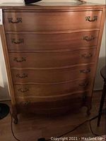 Front view of the tall boy dresser showing the four curved front drawers with brass handles.