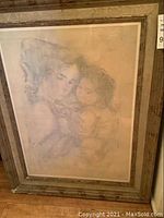 Framed lithograph showing woman and child artwork with visible frame wear.
