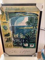 Framed Pablo Picasso 'Corte D' Azul poster with abstract coastal scene, black wood frame and protective corner guards.