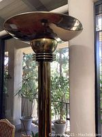 Close-up photo of the large reflective goldtone metal dish shade and pillar featuring decorative rings near the top