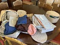 Collection of various quilted fabric storage bags in blue, pink, beige on a dark wood table with empty bags and fabric pouches for china and silverware storage.