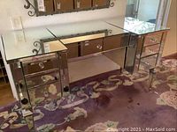Front view of entire mirrored vanity showing two side drawer towers and center drawer under glass top