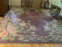 Full view of the rectangular purple floral rug laid flat on hardwood floor under furniture