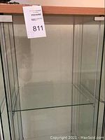 Full view inside of the glass cabinet showing four shelves and transparent glass sides.