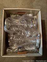 Box containing six silver plated candelabras wrapped in plastic.