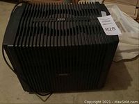 Side and top views of black Venta air purifier showing company logo, vent grille, control dial and electrical cord.