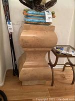 Front view of the wooden pedestal showing its curved and geometric multi-level design and natural wood finish