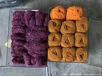 Purple and orange yarn stored in clear plastic container on concrete floor.