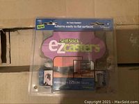 Photo of packaged Self Stick EZ Casters showing product name, usage instructions, and weight capacity on clear plastic blister pack.