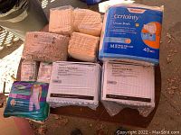 View of various packs of adult briefs and gauze sponges arranged on a surface, showing packaging and some product details.