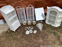 Photo showing two white wooden cabinets, a display cabinet, shoe racks, cloth hamper, mirror cabinet, and various hardware pieces laid on the ground.