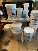 Full view of brewing equipment set showing various plastic buckets, lids, tubing, and other accessories arranged together.