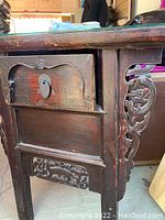 Side view showing single drawer with circular handle and carved detailing on the side panel.