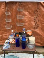 Full view of table with hanging baskets, metal wine rack, bowls of various materials, glass and plastic containers
