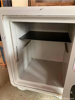 Open view of mechanical safe interior showing black metal shelf. Safe appears dirty and used.