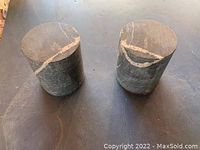 Two cylindrical migmatite rock book ends showing top surfaces with distinct mineral veins.