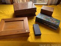 Top view of all five boxes on a yellow cloth background showing wood finishes and painted artwork