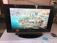 Samsung flat panel TV powered on displaying an aerial cityscape image.
