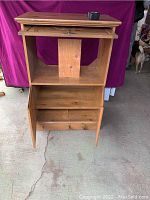 Front view of vintage wooden TV cabinet showing interior storage compartments including pull-out shelf and drawers, with visible scratches and wear.