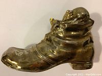 Side angle of vintage brass boot shoe figurine with visible wear and mouse inside.