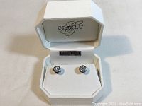 Open white Crislu box displaying the pair of round stud earrings with large cubic zirconia centers and sterling silver.