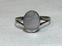 Front view showing the oval mother of pearl head with natural luster and polished sterling silver setting.