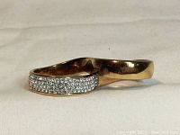 Side profile of the Swarovski two finger ring showing rose gold-plated band and the side encrusted with dozens of clear chatons crystals.